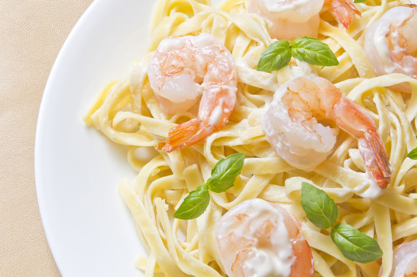 shrimp Fettuccini Alfredo with fresh basil leaves in fancy arrangement